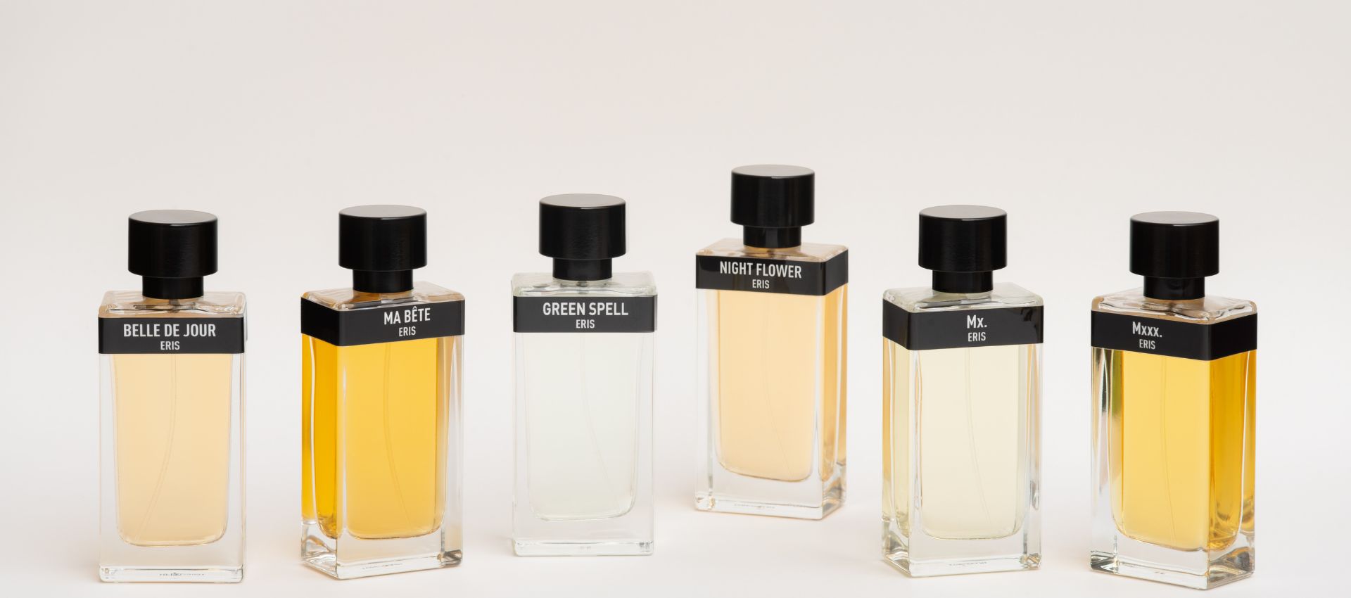 A lineup of perfume bottles from the brand Eris Parfums range. Starting on the left with Belle De Jour, Ma Bete, Green Spell, Night Flower, Mx. and Mxxx. all set against a white background. 
